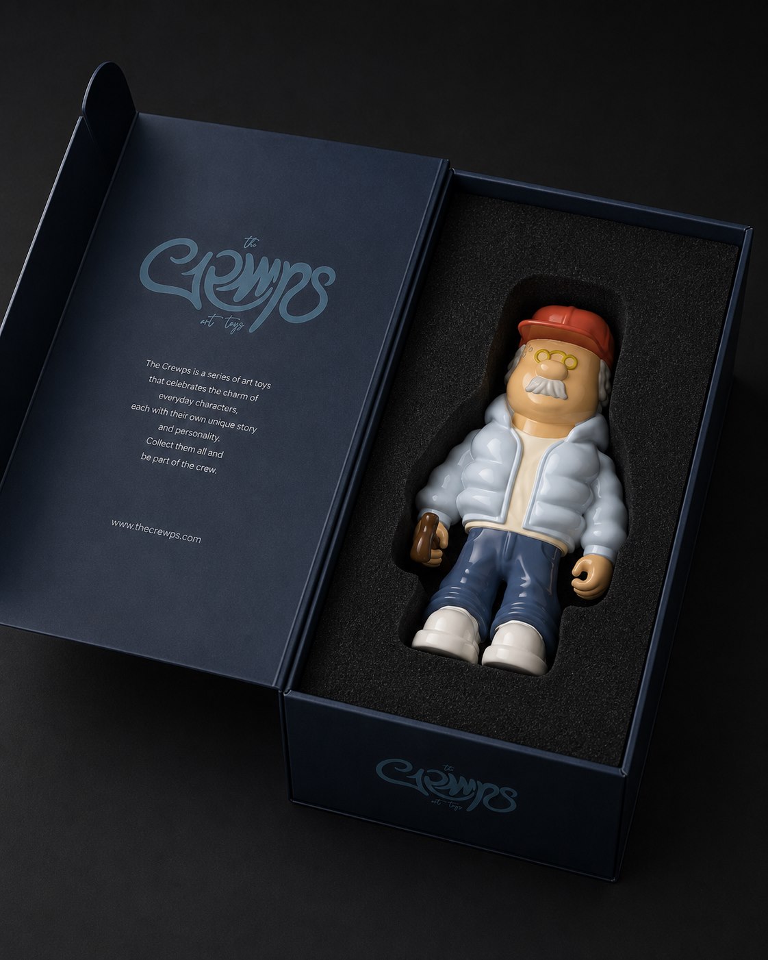 Packaging de The Grmps abierto: caja rígida azul noche con la figura GRMP en espuma troquelada